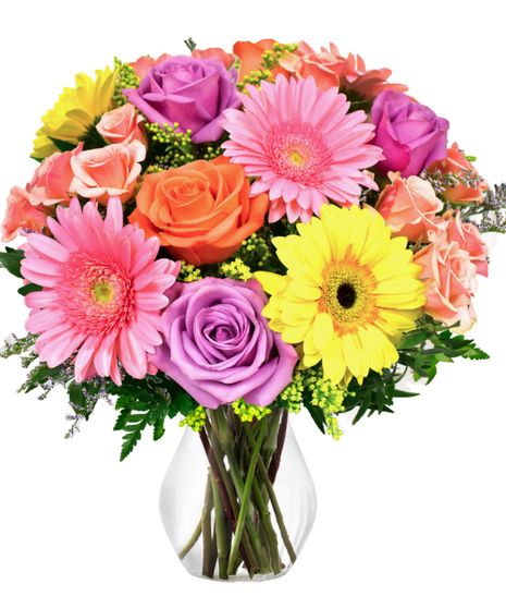 A colorful vase arrangement of gerbera daisies and roses.